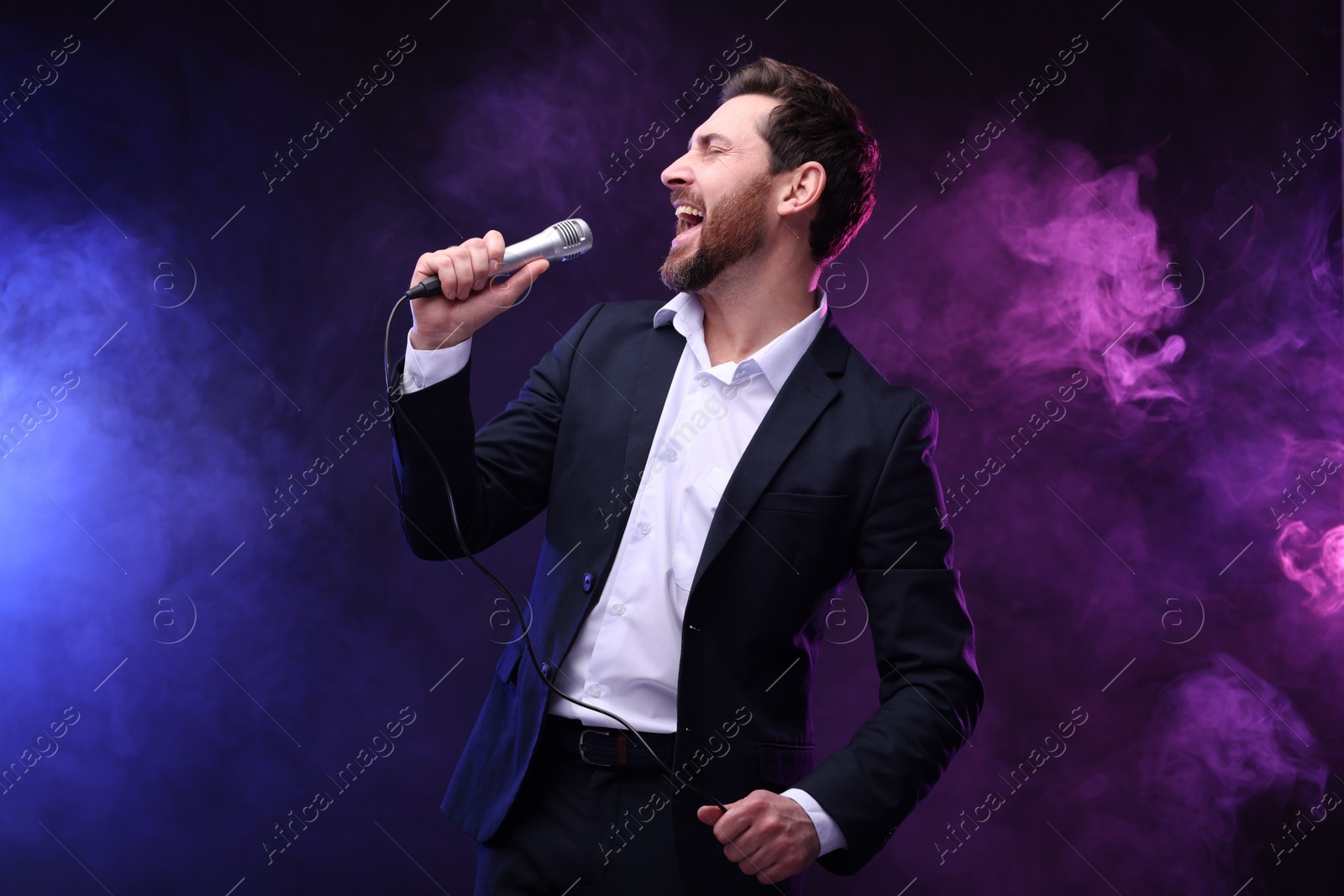 Photo of Emotional man with microphone singing in neon lights