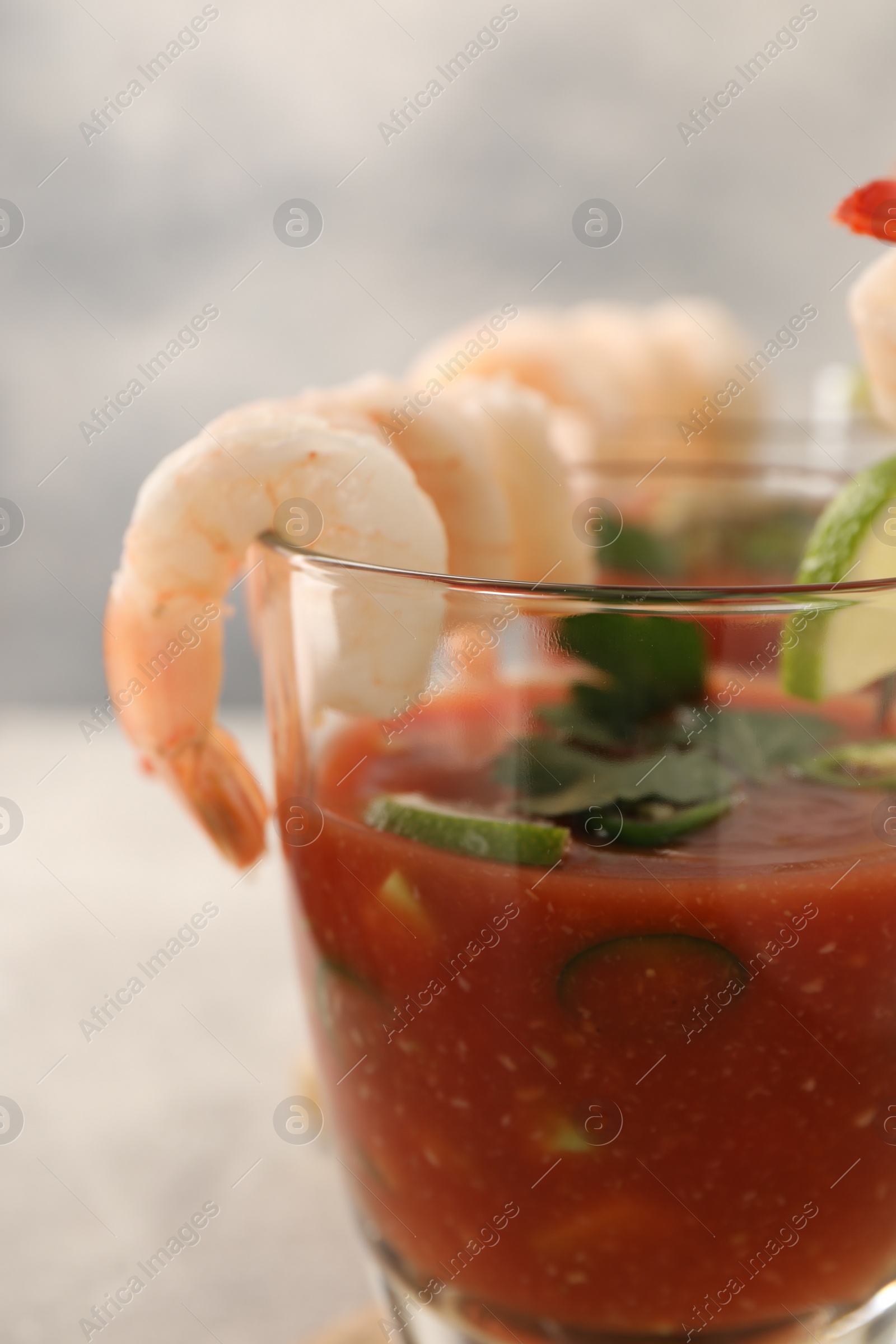 Photo of Tasty shrimp cocktail with sauce in glass on blurred background, closeup