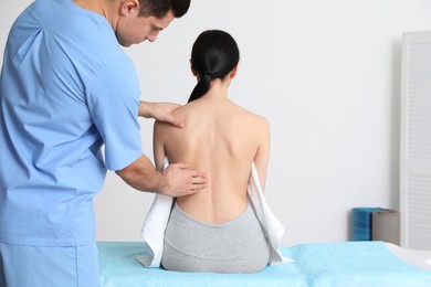 Photo of Orthopedist examining woman's back in clinic. Scoliosis treatment