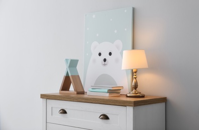 Photo of Modern white chest of drawers near light wall in child room. Interior design