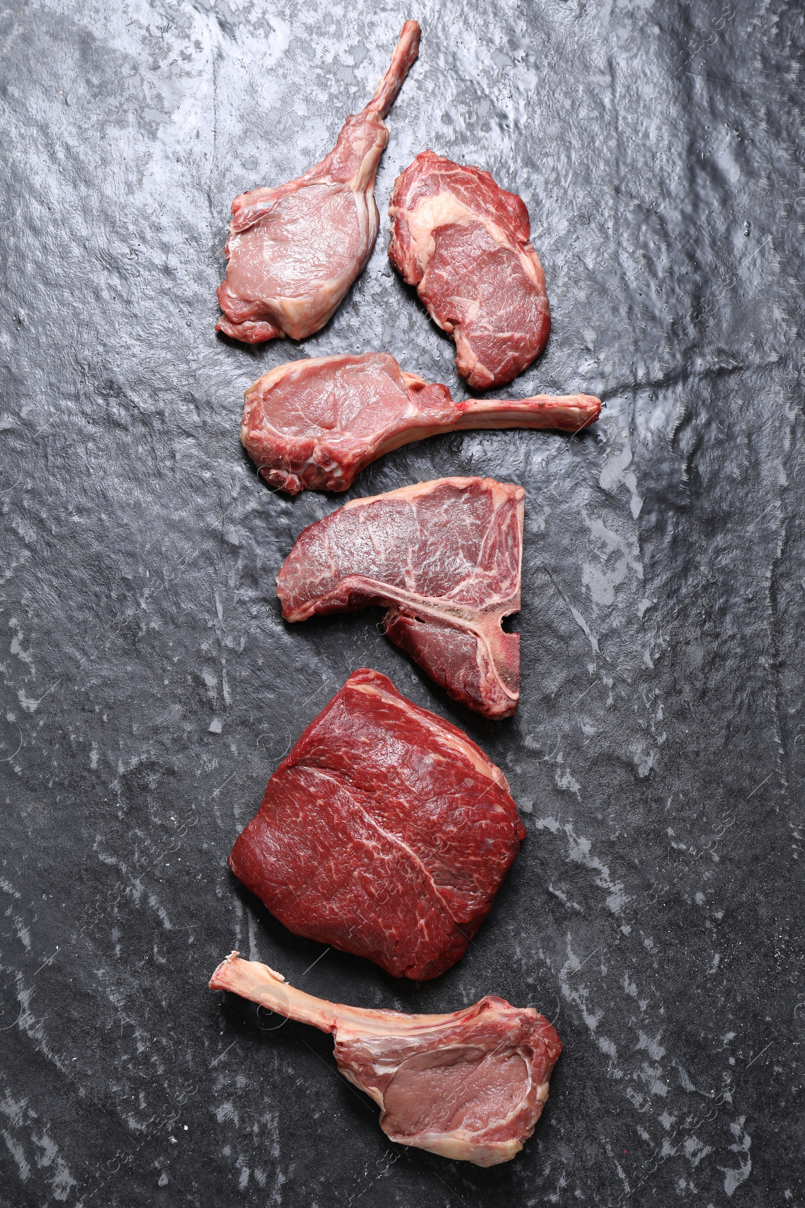 Photo of Fresh raw beef cuts on grey textured table, flat lay