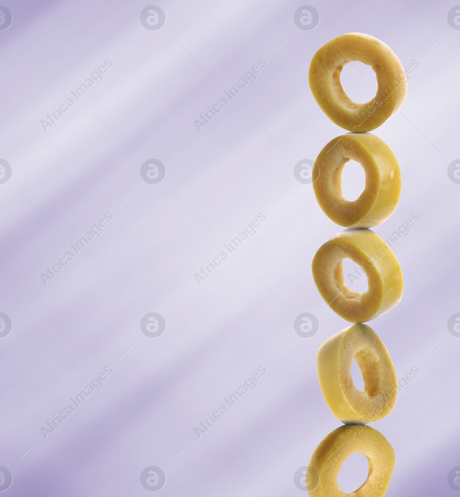 Image of Stacked slices of green olive on light purple gradient background, space for text