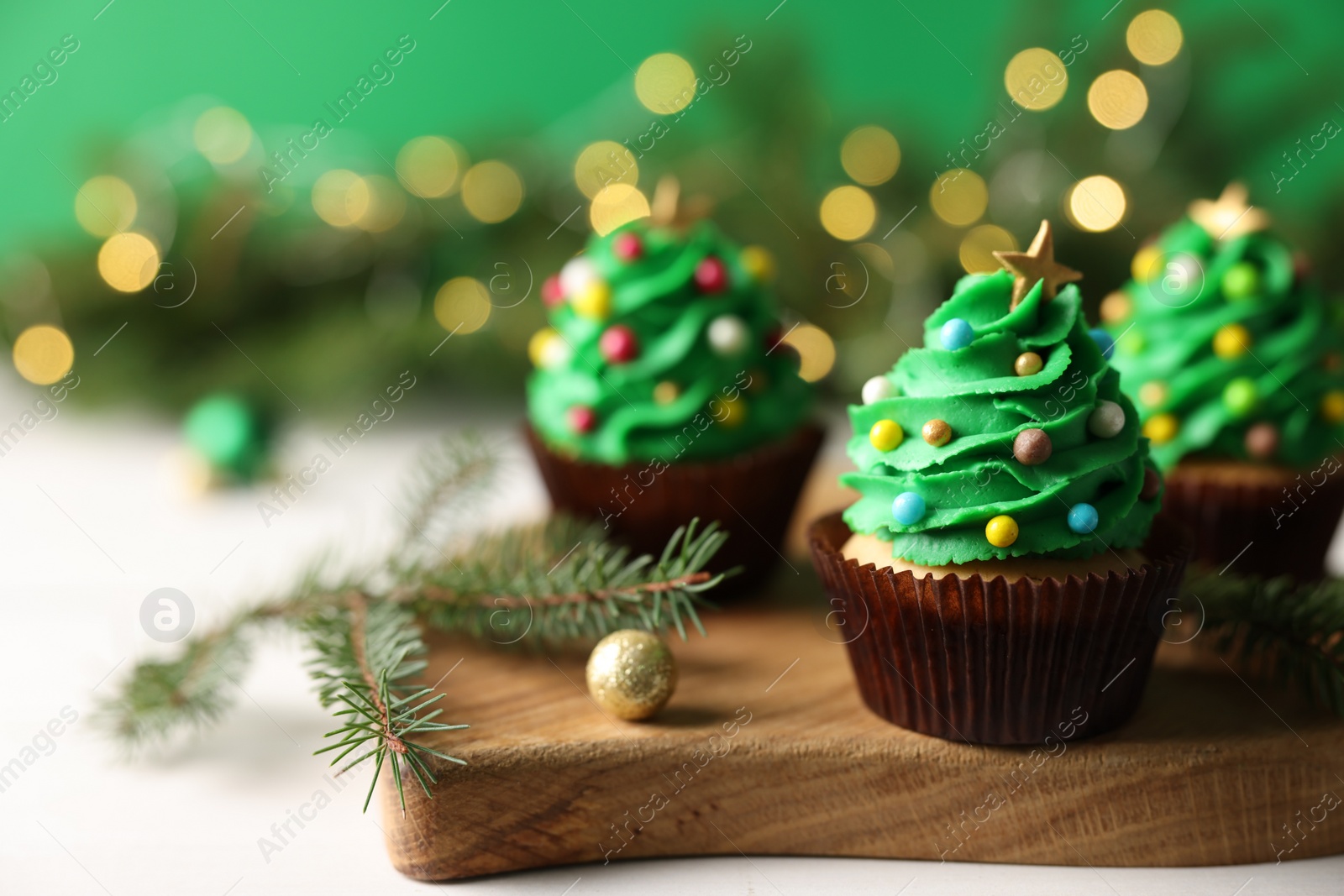 Photo of Tasty Christmas cupcakes on wooden board, closeup. Space for text