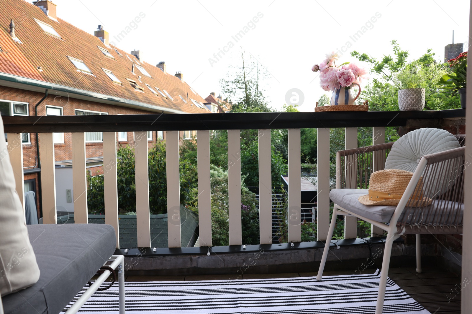 Photo of Different plants on railings and chair at cozy balcony outdoors