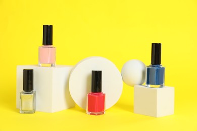 Photo of Stylish presentation of bright nail polishes in bottles on yellow background