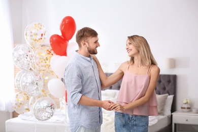 Photo of Young couple with air balloons in bedroom. Celebration of Saint Valentine's Day