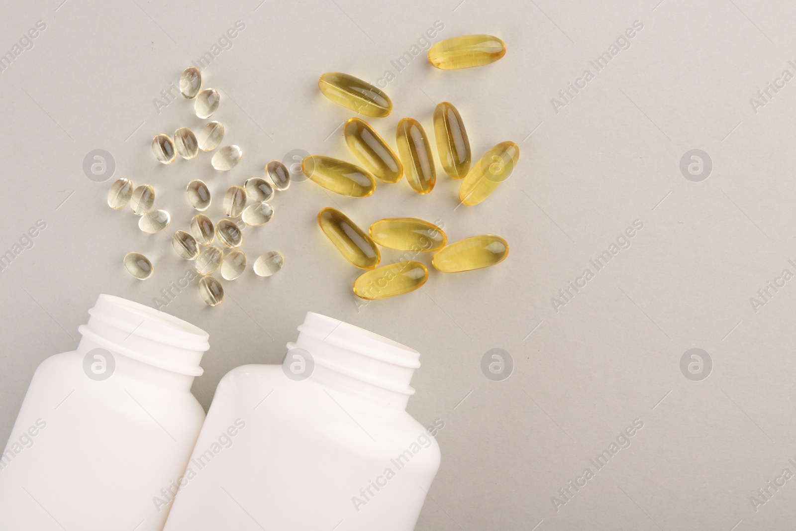 Photo of Bottles and different vitamin capsules on light grey background, flat lay. space for text