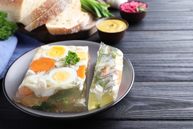 Photo of Delicious fish aspic served on black wooden table