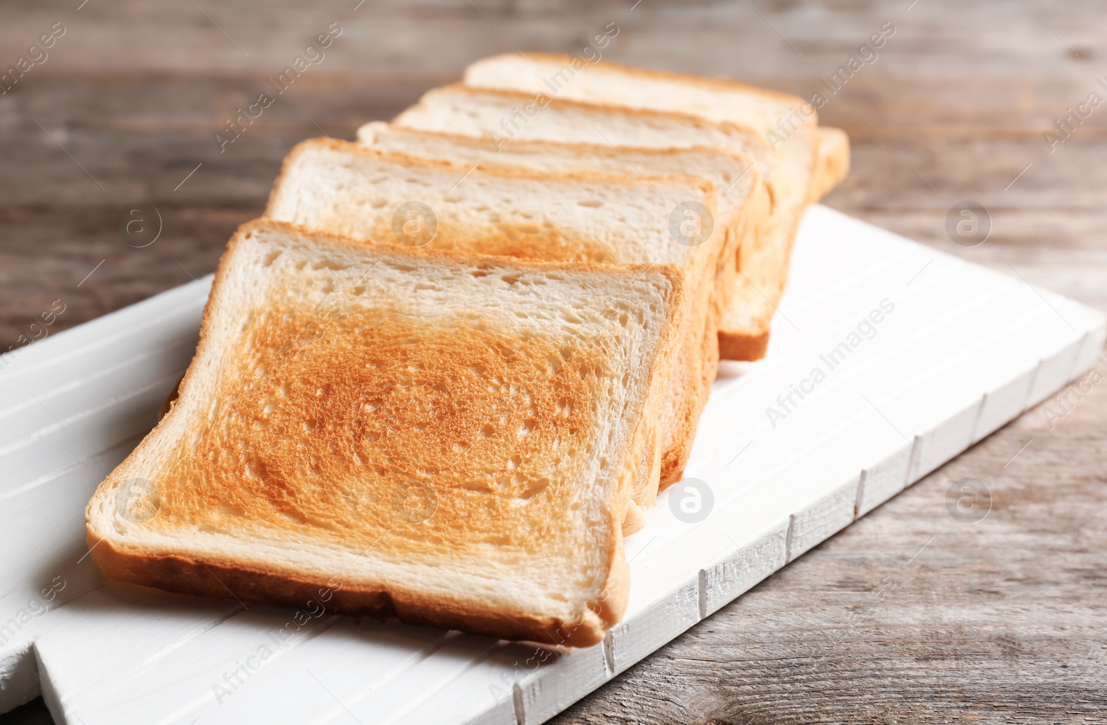 Photo of Board with toasted bread on wooden background