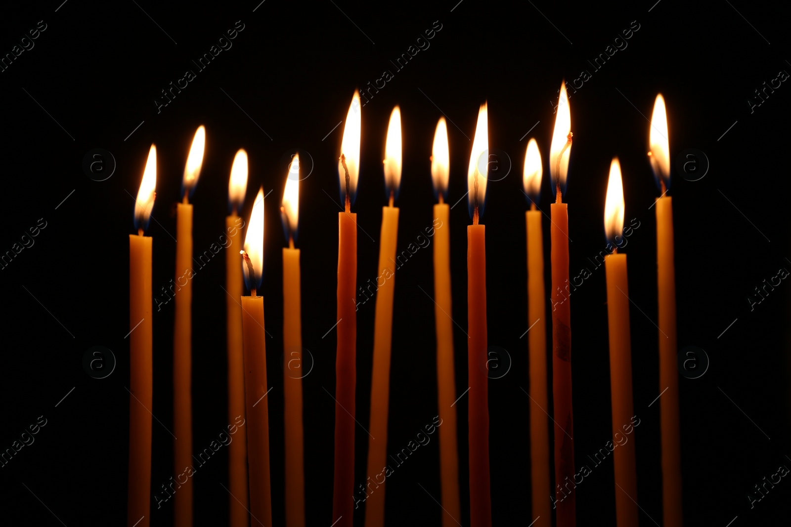 Photo of Many burning church candles on dark background