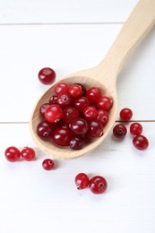 Photo of Spoon with fresh ripe cranberries on white wooden table, top view