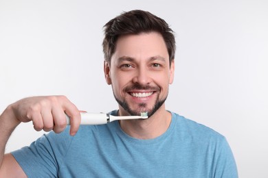 Happy man holding electric toothbrush on white background