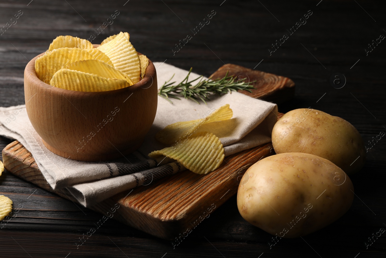 Photo of Bowl of crispy potato chips on wooden table