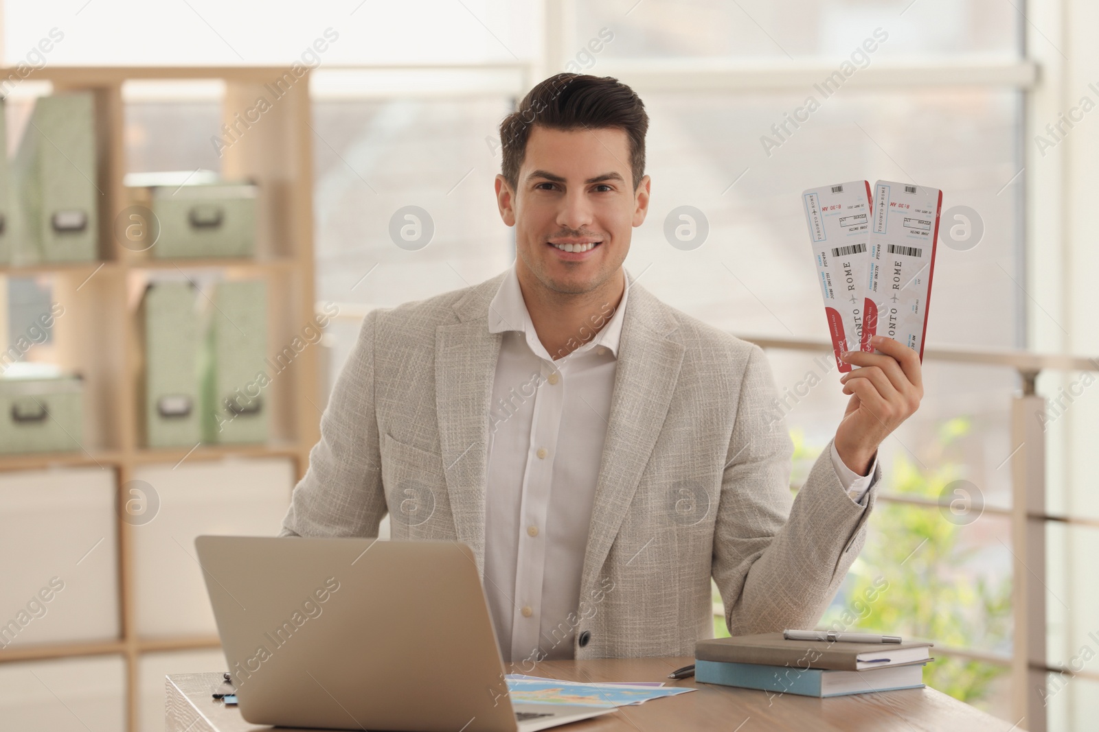 Photo of Travel agent with tickets at table in office