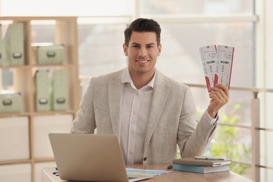 Travel agent with tickets at table in office