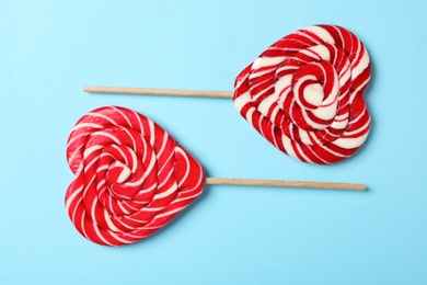 Photo of Sweet heart shaped lollipops on light blue background, flat lay. Valentine's day celebration