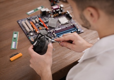 Male technician repairing computer fan at table, closeup