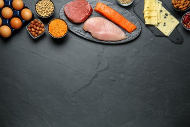 Different fresh products on black table, flat lay and space for text. Sources of essential amino acids