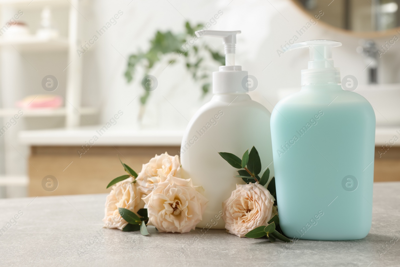 Photo of Dispensers of liquid soap and roses on light grey table in bathroom, space for text