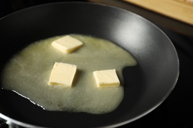 Photo of Melting butter in frying pan on black table, closeup