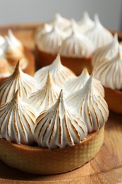 Photo of Tartlets with meringue on wooden table, closeup. Tasty dessert