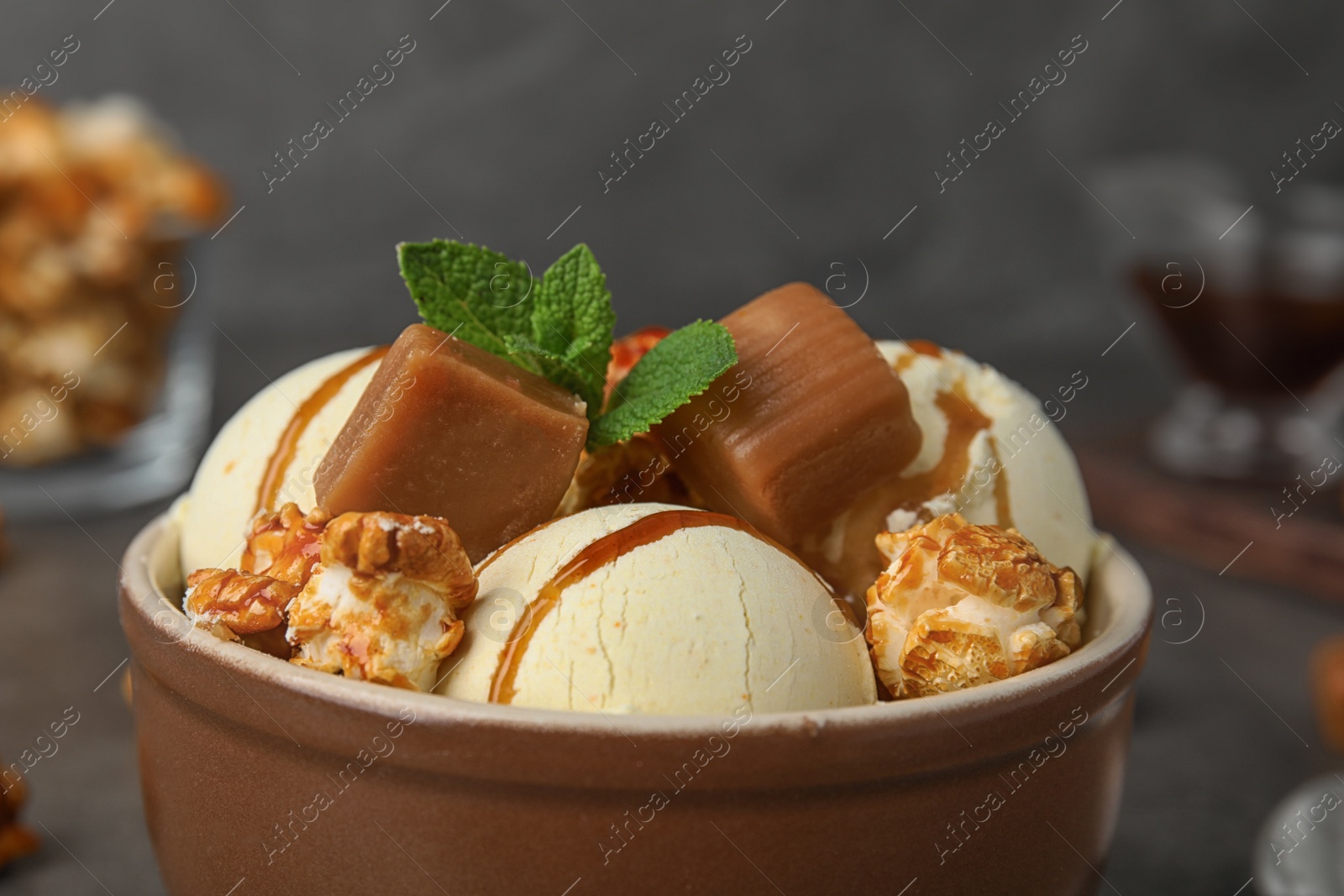 Photo of Delicious ice cream with caramel and popcorn in bowl on table, closeup
