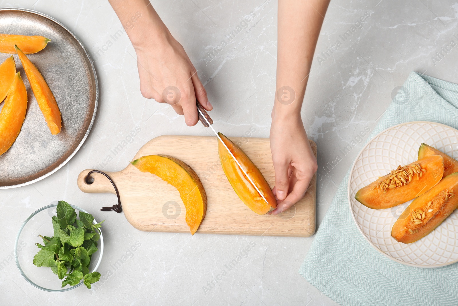 Photo of Woman slicing fresh ripe melon at light table, top view