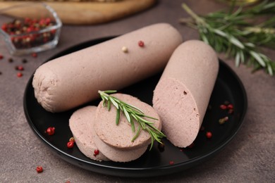 Photo of Delicious liver sausages with rosemary on brown textured table