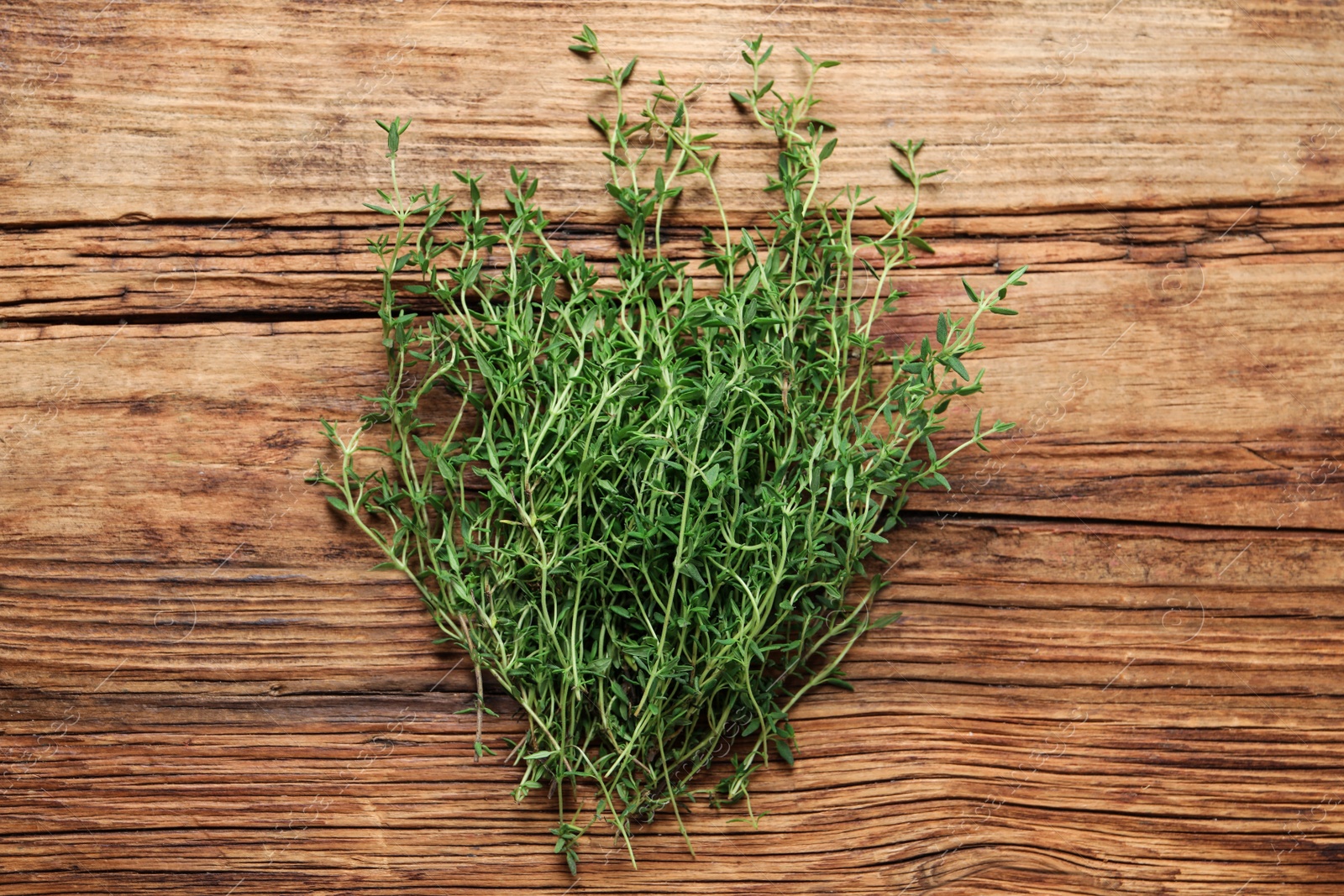 Photo of Bunch of aromatic thyme on wooden table, top view