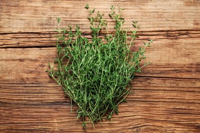 Photo of Bunch of aromatic thyme on wooden table, top view