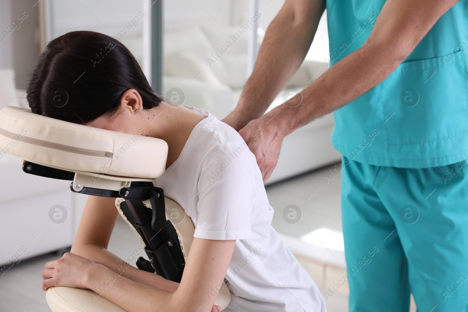 Photo of Woman receiving massage in modern chair indoors