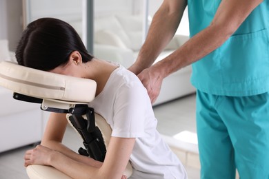 Woman receiving massage in modern chair indoors