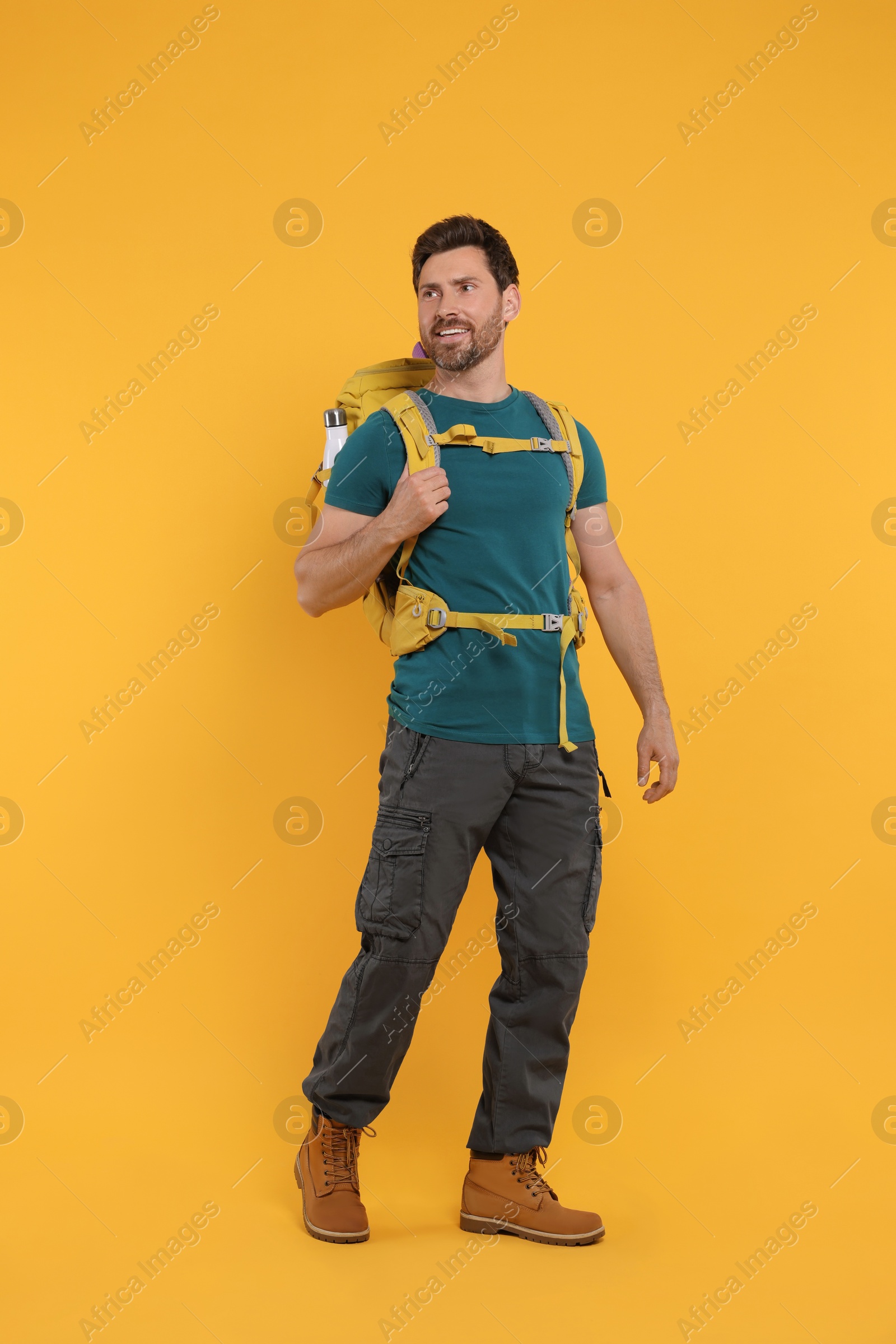 Photo of Happy man with backpack on orange background. Active tourism