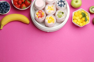 Yogurt maker with jars and different fruits on pink background, flat lay. Space for text