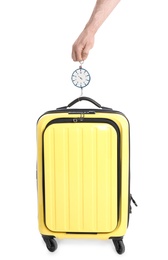 Man weighing stylish suitcase on white background