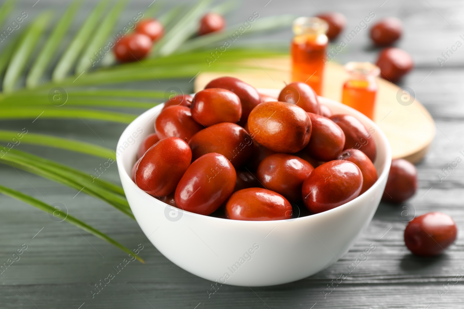 Photo of Palm oil fruits in bowl on grey wooden table, closeup