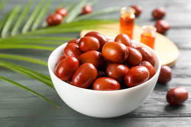 Palm oil fruits in bowl on grey wooden table, closeup