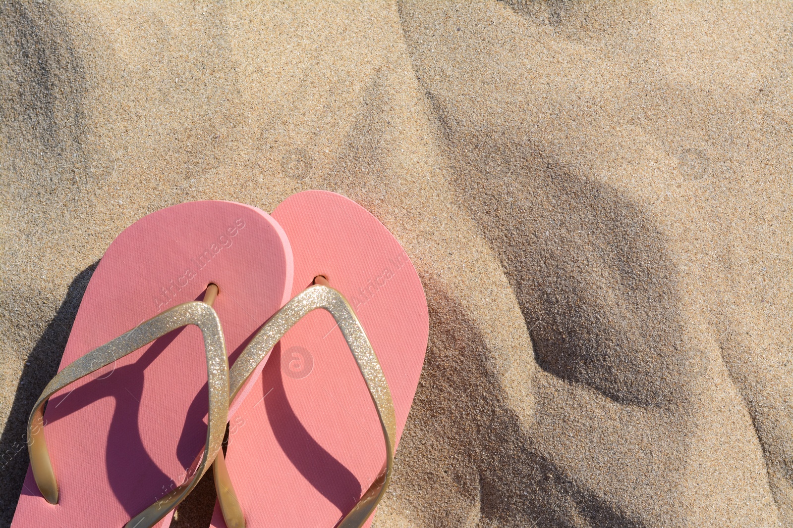 Photo of Stylish flip flops on sandy beach, flat lay. Space for text