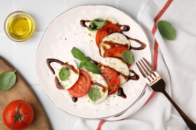 Delicious Caprese salad with balsamic vinegar served on white tiled table, flat lay