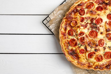 Delicious homemade quiche with prosciutto and tomatoes on white wooden table, top view. Space for text