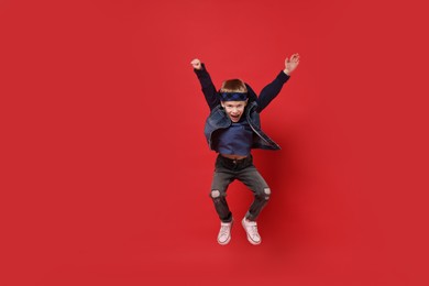 Happy little boy dancing on red background