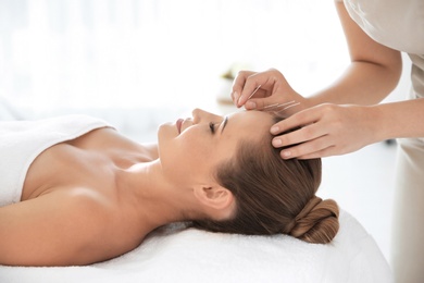 Photo of Young woman undergoing acupuncture treatment in salon