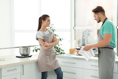 Photo of Young couple with oven sheet in kitchen