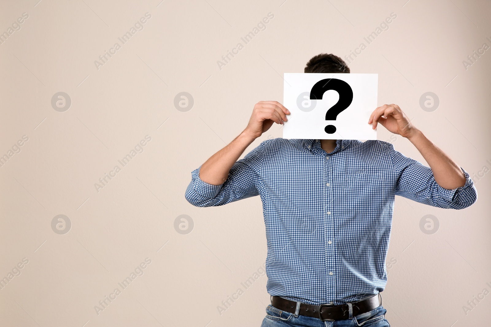 Photo of Man holding paper with question mark on grey background, space for text