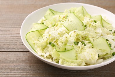 Photo of Tasty salad with Chinese cabbage, cucumber and green onion in bowl on wooden table, closeup