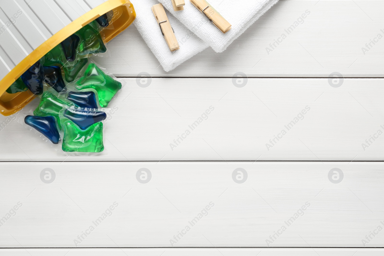 Photo of Laundry capsules on white wooden table, flat lay. Space for text