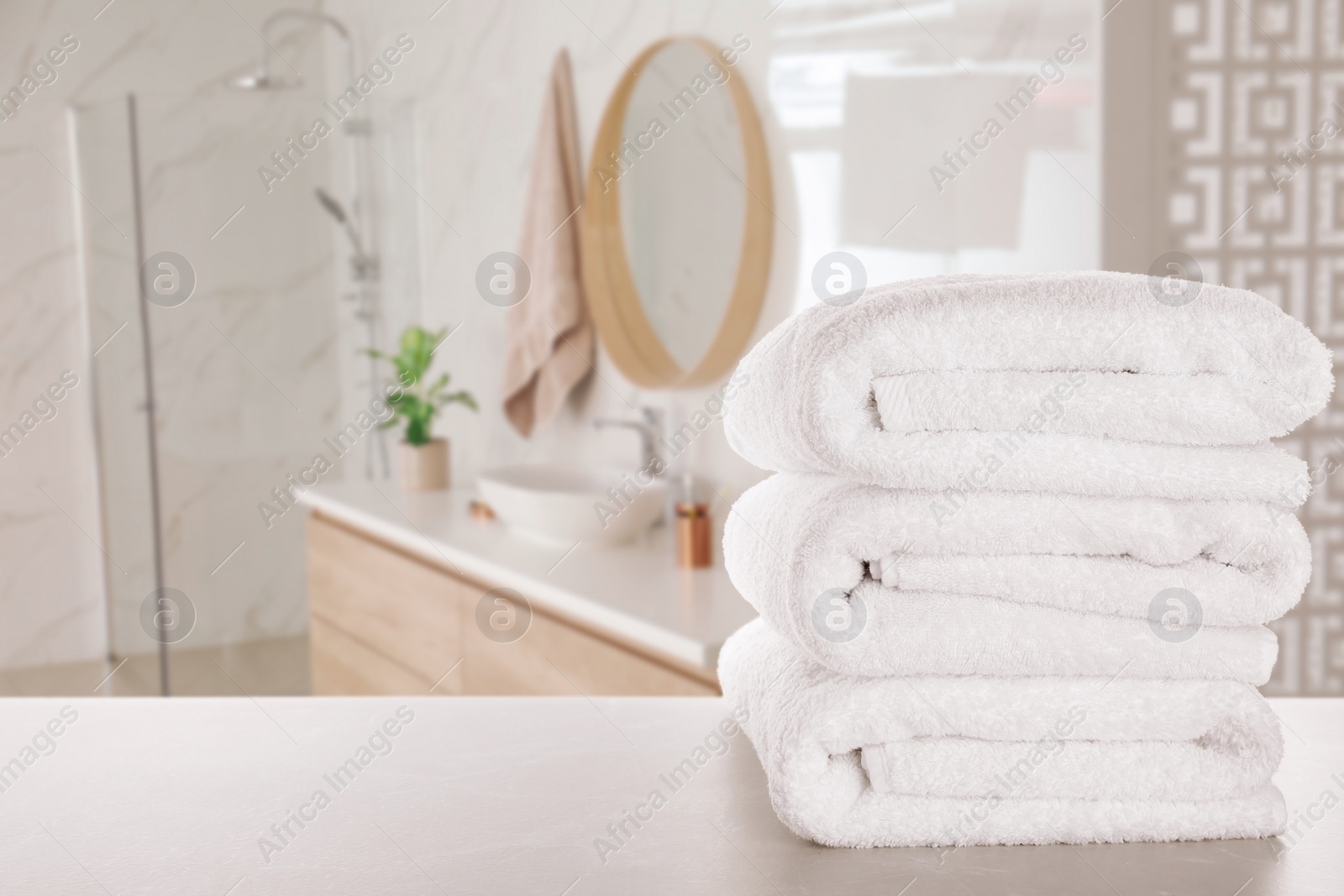 Image of Stack of fresh towels on light grey table in bathroom. Space for text
