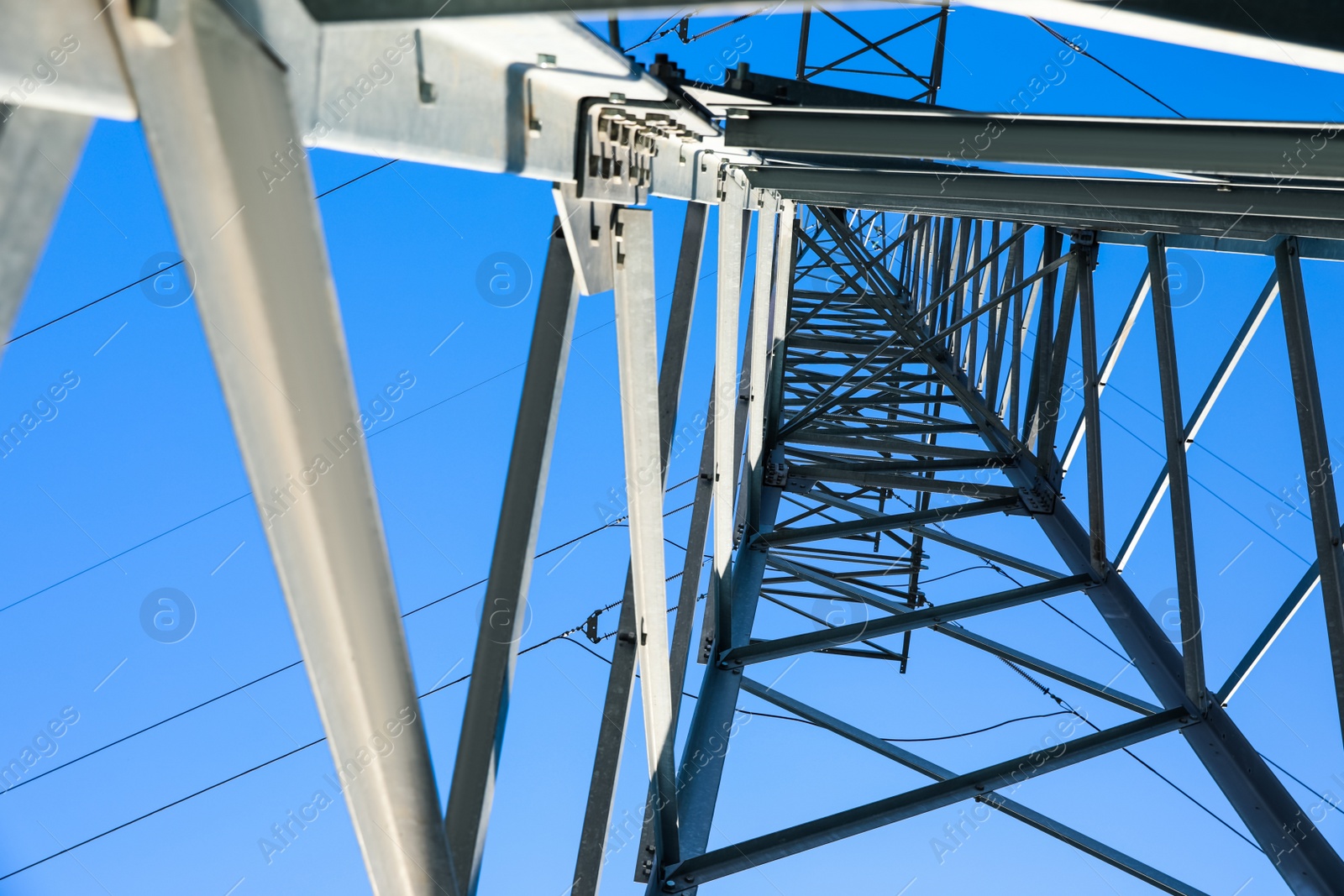 Photo of Modern high voltage tower against blue sky, low angle view