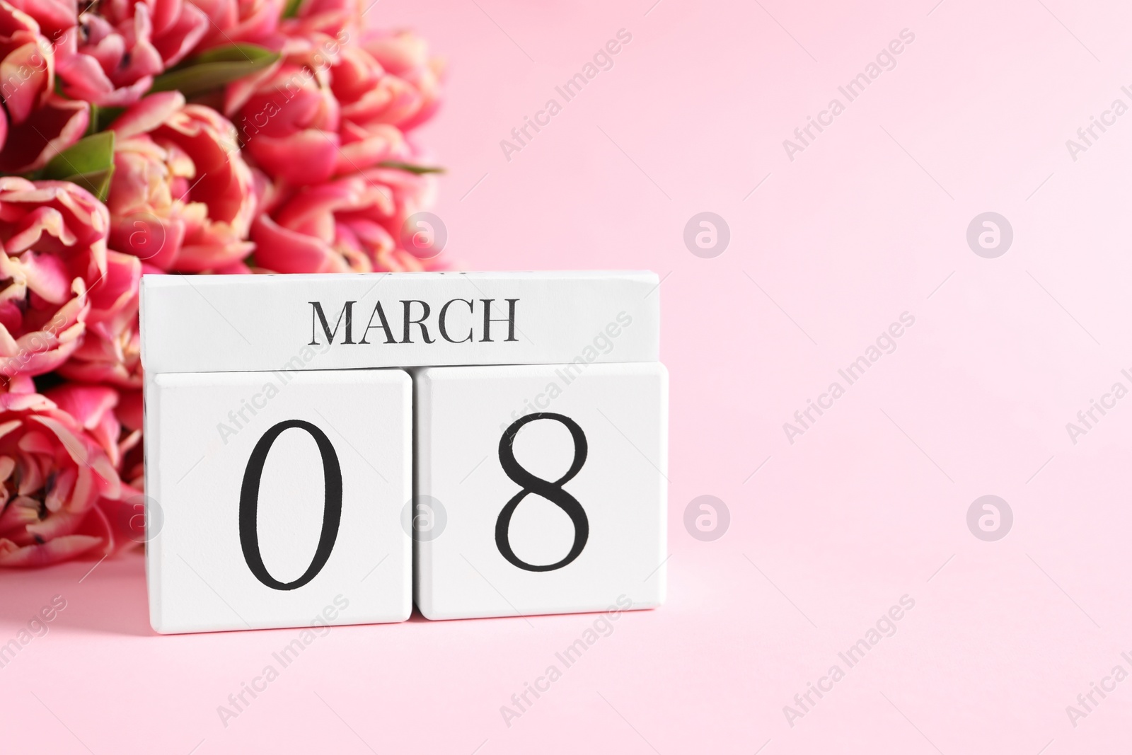 Photo of International Women's day - 8th of March. Block calendar and bouquet of beautiful tulips on pink background. Space for text