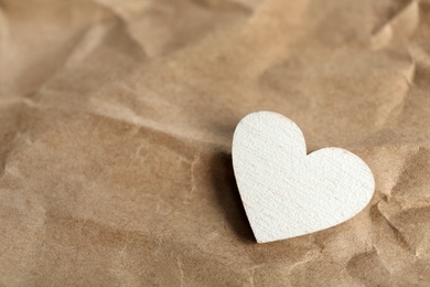 Photo of White wooden heart on crumpled kraft paper, space for text. St. Valentine's day